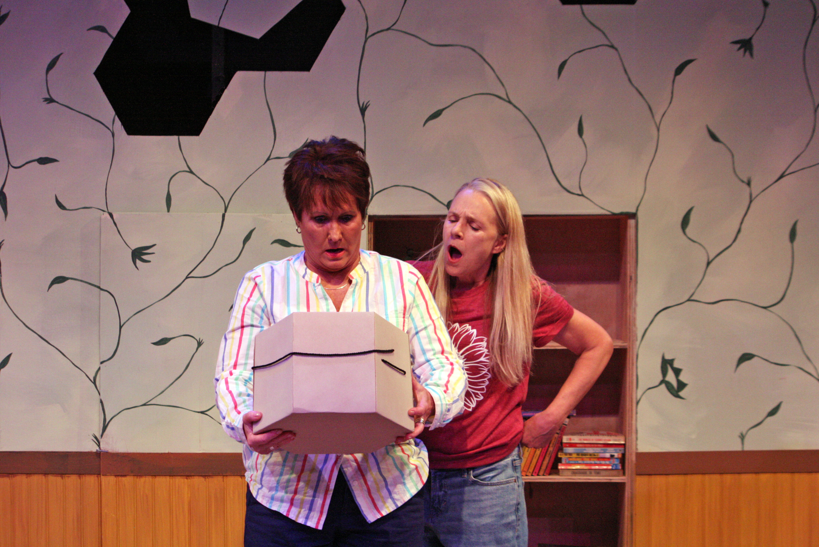 Two women looking in a hat box with shocked faces