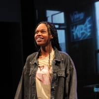 A woman with long dark hair, wearing a jacket looking up and smiling