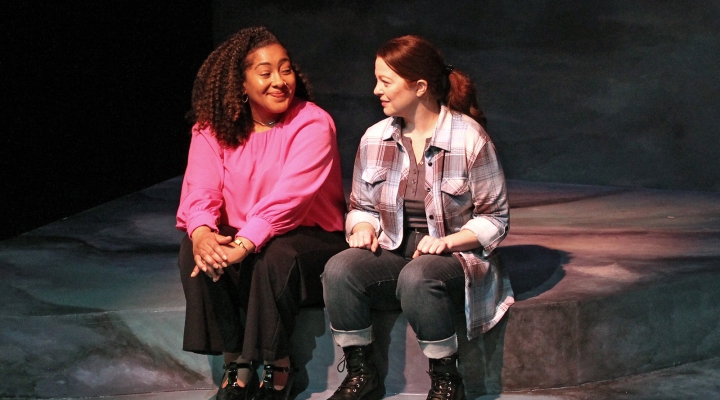 Two women sitting facing each other, smiling.